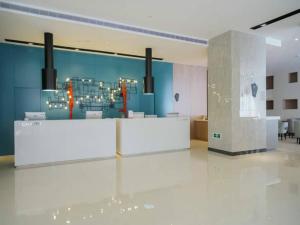 a lobby with a white counter and a blue wall at Echarm Hotel Xiamen Airport Hi-tech Park in Xiamen