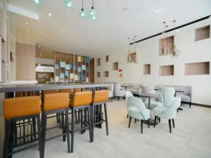 a restaurant with a bar with chairs and tables at Echarm Hotel Xiamen Airport Hi-tech Park in Xiamen