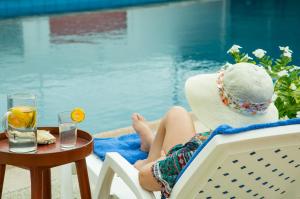 una mujer con sombrero sentada en una silla junto a una piscina en Hotel RC Tonsupa, en Tonsupa