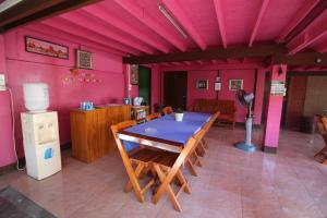 a dining room with a table and a pink wall at Baan Bua Homestay in Chiang Rai