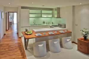 una cucina con bancone e quattro sedie bianche di Osho Luxury Beachfront Apartments a Bophut
