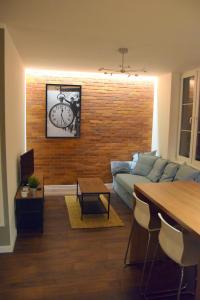 a living room with a couch and a clock on a brick wall at Apartament Marii Ludwiki in Koszalin
