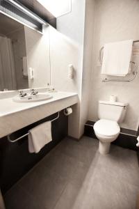 a bathroom with a toilet and a sink and a mirror at Supreme Inns Boston in Swineshead