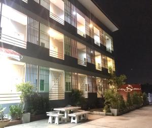 un edificio con dos mesas de picnic delante de él en The Rich Home, en Nakhon Ratchasima