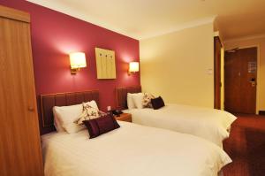 a hotel room with two beds and two lamps at Supreme Inns in Swineshead