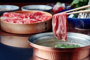 a piece of meat being dipped into a bowl of soup at Sotetsu Fresa Inn Ginza Sanchome in Tokyo