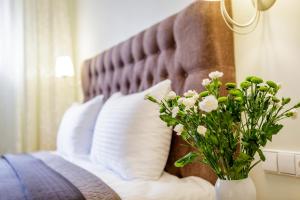 ein Bett mit weißen Kissen und eine Vase mit Blumen in der Unterkunft Vila Elegancija in Palanga