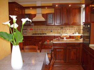 una cocina con armarios de madera y un jarrón con flores blancas en Casa Coccinella en Oggebbio