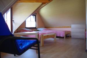 a attic room with two beds and a chair at Ahorn II in Rydzewo