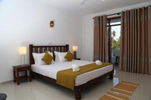 um quarto com uma cama grande e uma janela em Hikka Regent Hotel em Hikkaduwa