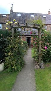 a garden with a wooden arch with flowers at Hillside Bed and Breakfast in Bedale