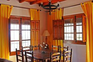 a dining room with a table and yellow curtains at Villa del Sol in Frigiliana