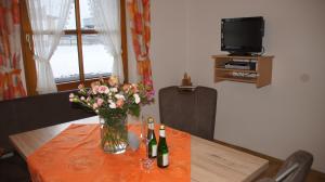 einen Tisch mit einer Vase aus Blumen und Weinflaschen in der Unterkunft Apart Höferauer Hof in Kappl