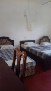 Cette chambre comprend 2 lits et une chaise. dans l'établissement Kitolie Home and Lodge, à Moshi