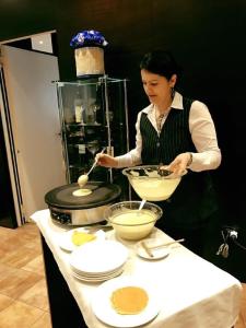a woman standing in a kitchen preparing food at Hotel Principe di Piemonte in Rimini