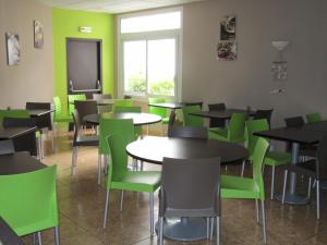 a dining room with tables and green chairs at La Sterne in Saint-Gilles-Croix-de-Vie