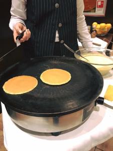 a person holding a pan with pancakes on it at Hotel Principe di Piemonte in Rimini