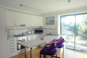 a kitchen with a large white counter and purple chairs at Moon House in Diamond Creek