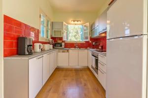 ガイオスにあるVilla Mantiの白いキャビネットと赤いタイルのキッチン