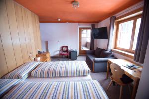 a bedroom with a bed and a desk and a couch at Hotel Hold AG in Arosa
