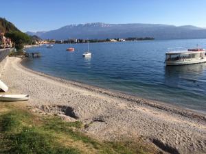 a beach with boats in a large body of water at AGORÀ suite in Gardone Riviera +7 photos