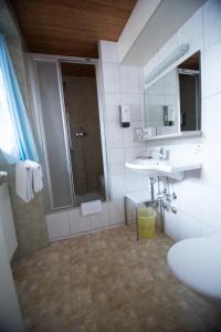 a bathroom with a shower and a sink and a mirror at Hotel Hold AG in Arosa