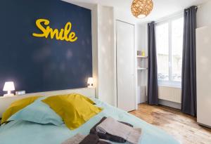 シャルルヴィル・メジエールにあるSuite Rimbaudの壁に笑顔の看板が付いたベッドルーム