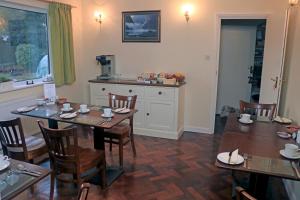 a dining room with tables and chairs and a kitchen at Dawyk Beech Guesthouse in Fleet
