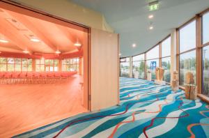 een grote kamer met een kleurrijk tapijt en ramen bij Kurzentrum Waren (Müritz) in Waren