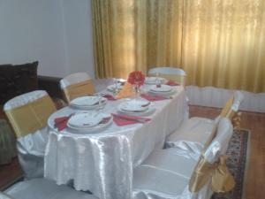 une table avec un chiffon de table blanc et des chaises avec des assiettes et des bols dans l'établissement Nopti de Vara Transfăgărășan, à Căpăţîneni-Pămînteni