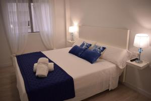 a bedroom with a white bed with blue pillows at Apartamento Chapaprieta 1 in Torrevieja