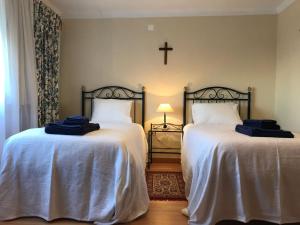 a bedroom with two beds and a cross on the wall at A Casa da Avó Leonor in Idanha-a-Nova