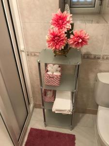 un baño con un estante con flores rosas. en A Casa da Avó Leonor, en Idanha-a-Nova