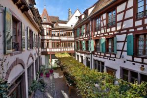 une allée de bâtiments avec des plantes en pot et des fleurs dans l'établissement Relais & Châteaux La Maison Des Têtes, à Colmar