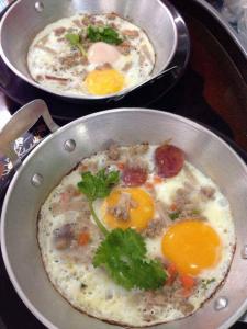 two pans of food with eggs on a stove at Sukwimol Place in Phitsanulok