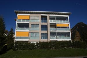 a tall apartment building with a mountain in the background at Blumenau in Davos