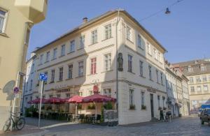 ein großes weißes Gebäude mit roten Sonnenschirmen auf einer Straße in der Unterkunft Swarg Living City Center Bamberg in Bamberg