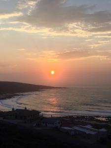 een zonsondergang boven de oceaan met de zon in de lucht bij Captain Sunshine Guest House in Jongensfontein