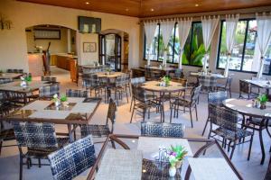 a restaurant with tables and chairs and windows at Pousada Valle das Colinas in Tiradentes