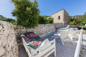um pátio com cadeiras, uma mesa e uma parede de pedra em Villa Tipica "Arancelli 11" em Ragusa