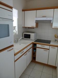 a kitchen with white cabinets and a white microwave at Océane Flore appart vue mer in Les Sables-dʼOlonne