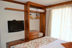 um quarto com uma cama e uma televisão em Bangalo-Yacamim Praia do Curral em Ilhabela