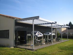 un pavillon avec des tables et des parasols dans une cour dans l'établissement Résidence Hôtelière des Ondes, à Saint-Lys