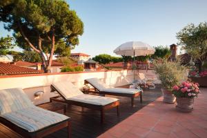 a group of chairs and an umbrella on a patio at Forte Inn in Forte dei Marmi