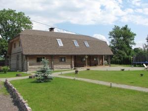 a large log cabin with a grass yard in front of it at Vizbulites in Pulkarne