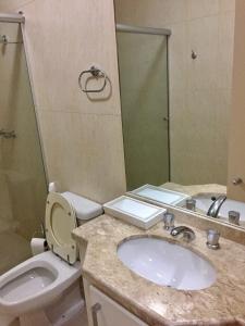 a bathroom with a sink and a toilet and a mirror at Apartamento a beira mar in Capão da Canoa +14 photos