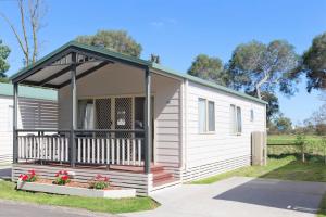 a white tiny house with a porch and flowers at BIG4 Dandenong Tourist Park in Dandenong