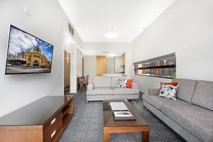 uma sala de estar com um sofá e uma mesa em Melbourne CBD Central Apartment Hotel Official em Melbourne