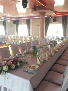 a long table in a room with white tables and chairs at Gościniec Rycerski in Malbork