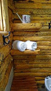un baño de madera con toallas, una taza y un lavabo en costa bonita el bosque, en Villa Pehuenia